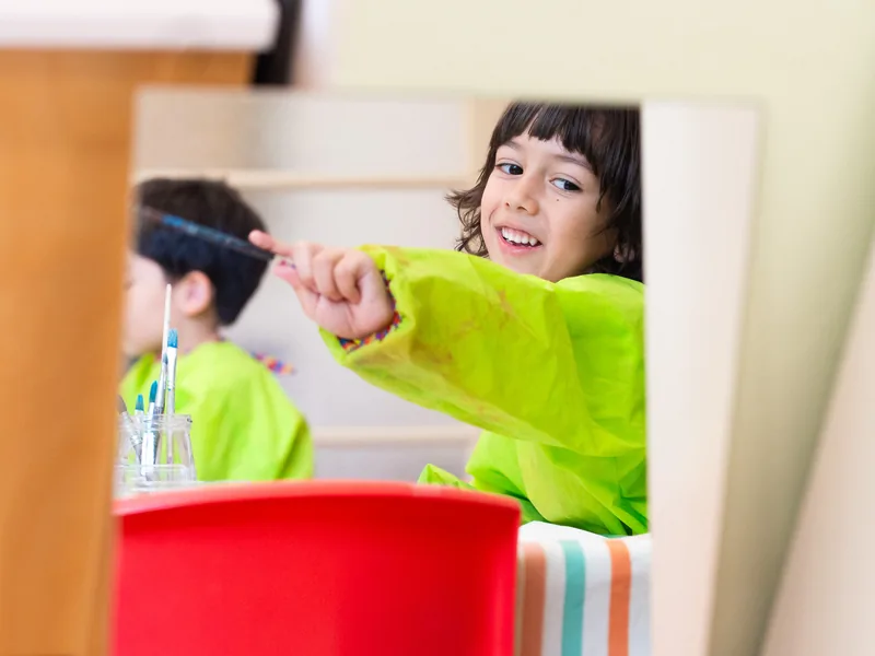 A child in a smock smiling during art class