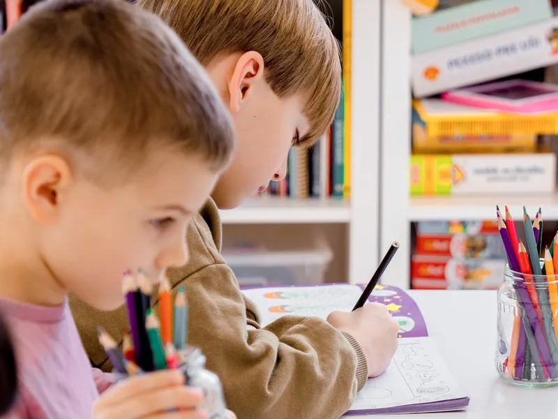 A Kindergarten boy practicing writing at his desk
