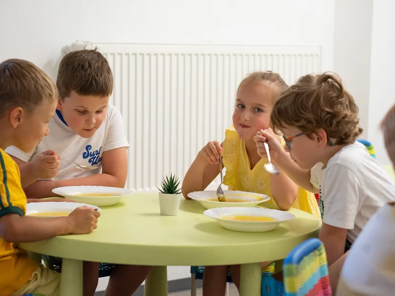 Children eating a meal together at the classroom table