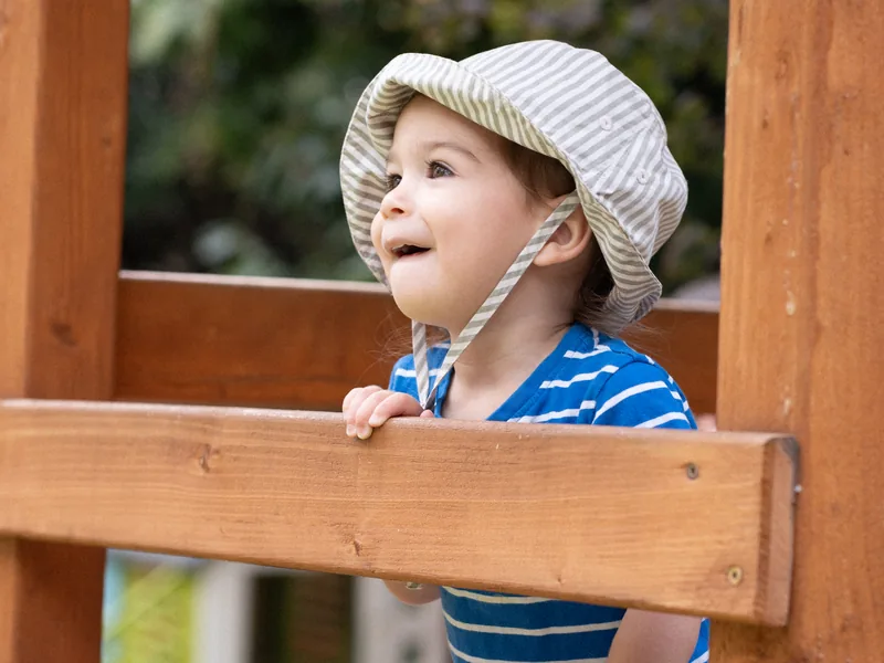 A Nursery child looking out from the playhouse in the school garden